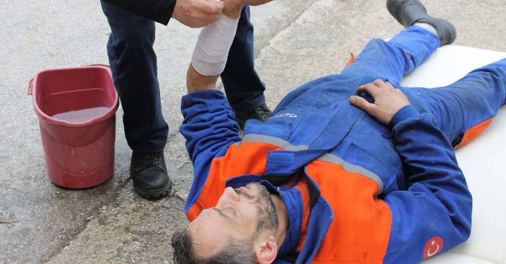 A worker in overalls laying on the floor after a workplace accident.